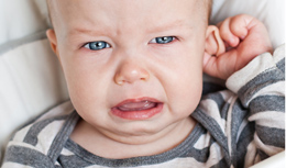 Unhappy infant tugging on ear, a possible sign of an ear infection